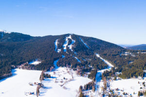 Luftaufnahme des Spicak-Bergs mit Skipisten in der Nähe von Zelezna Ruda. Winterurlaubsort im Nationalpark