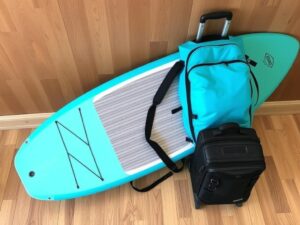 Moai 10'6 Ultra Light SUP Board zusammengerollt im Rucksack neben Reisegepäck
