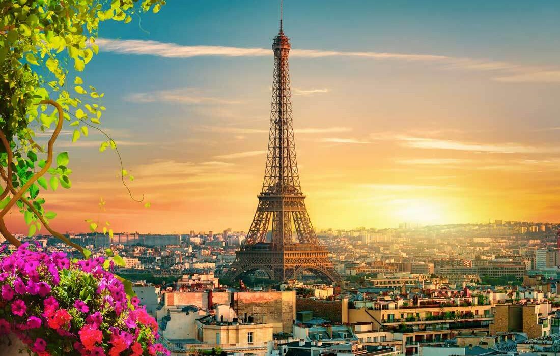 Der Eiffelturm Paris bei Sonnenuntergang, beleuchtet in goldenem Licht mit der Pariser Skyline im Hintergrund