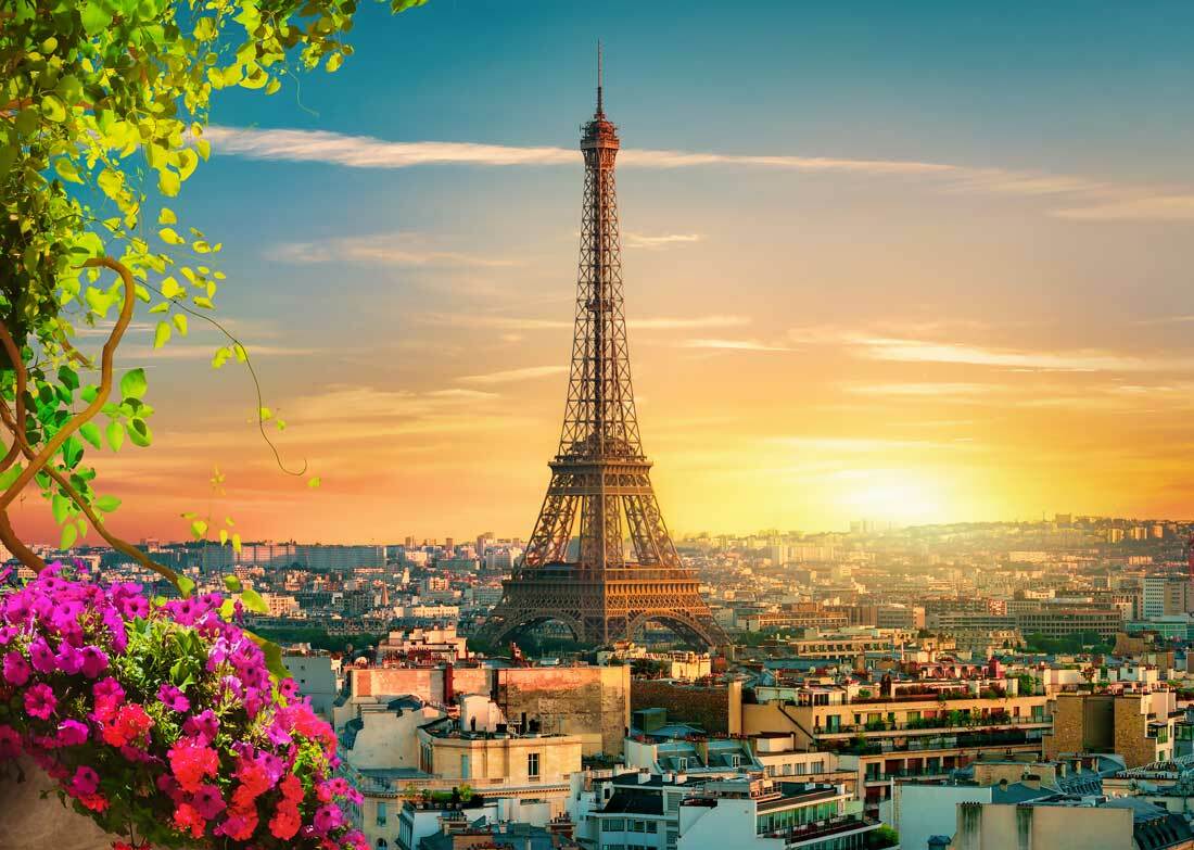 Der Eiffelturm Paris bei Sonnenuntergang, beleuchtet in goldenem Licht mit der Pariser Skyline im Hintergrund