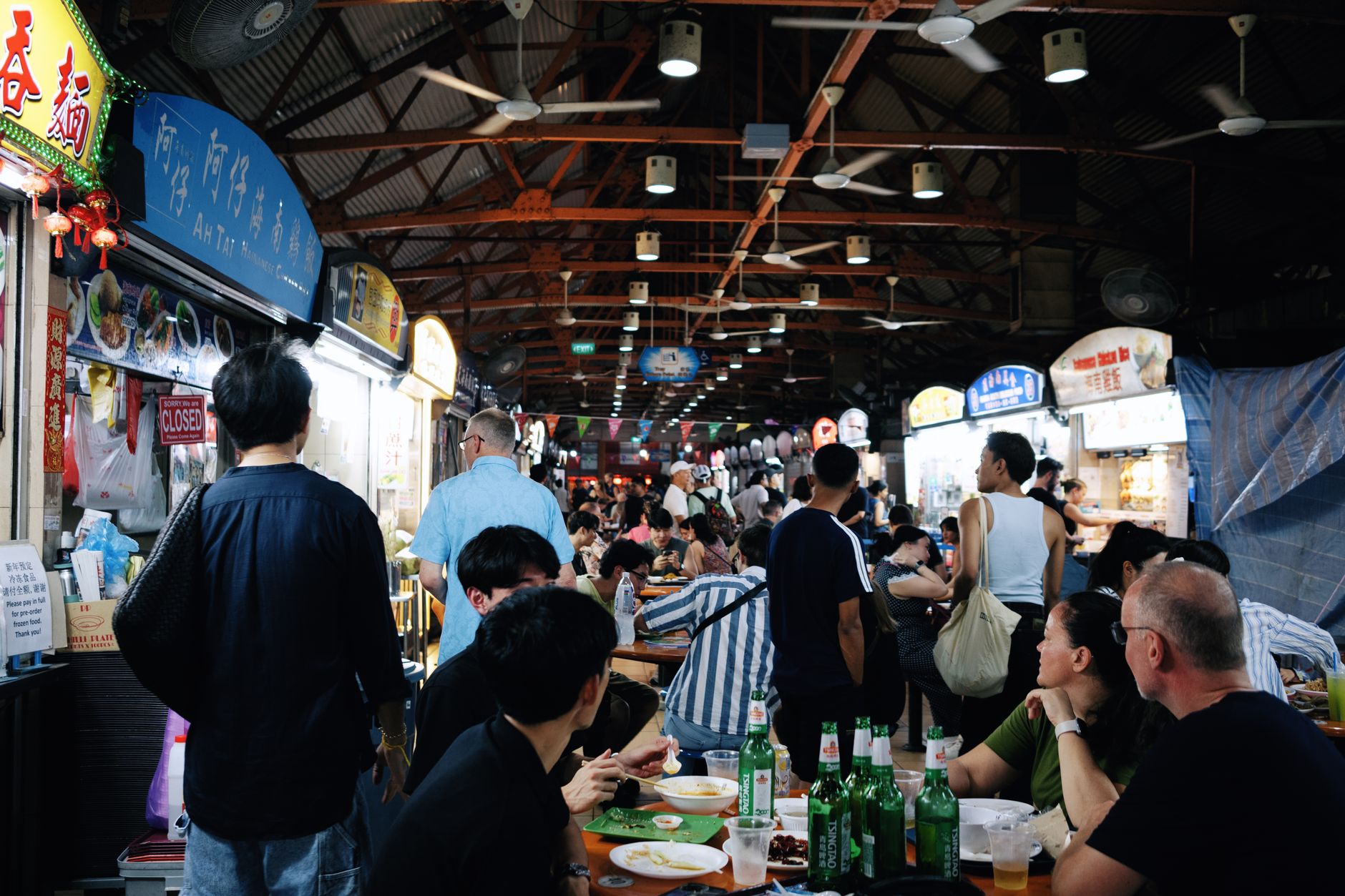 Essensstände und Gäste an Tischen in einem Hawker Centre in Singapur