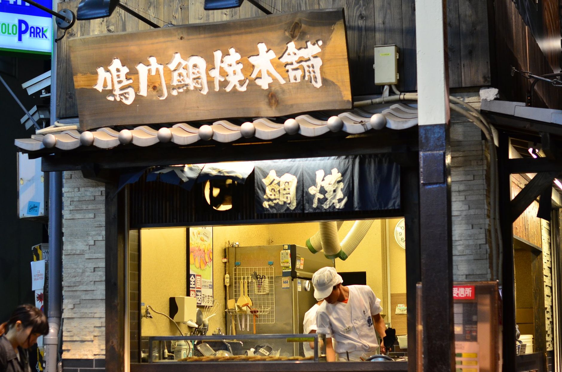 Koch wendet Takoyaki-Teigkugeln an einem Stand in Dotonbori in Osaka