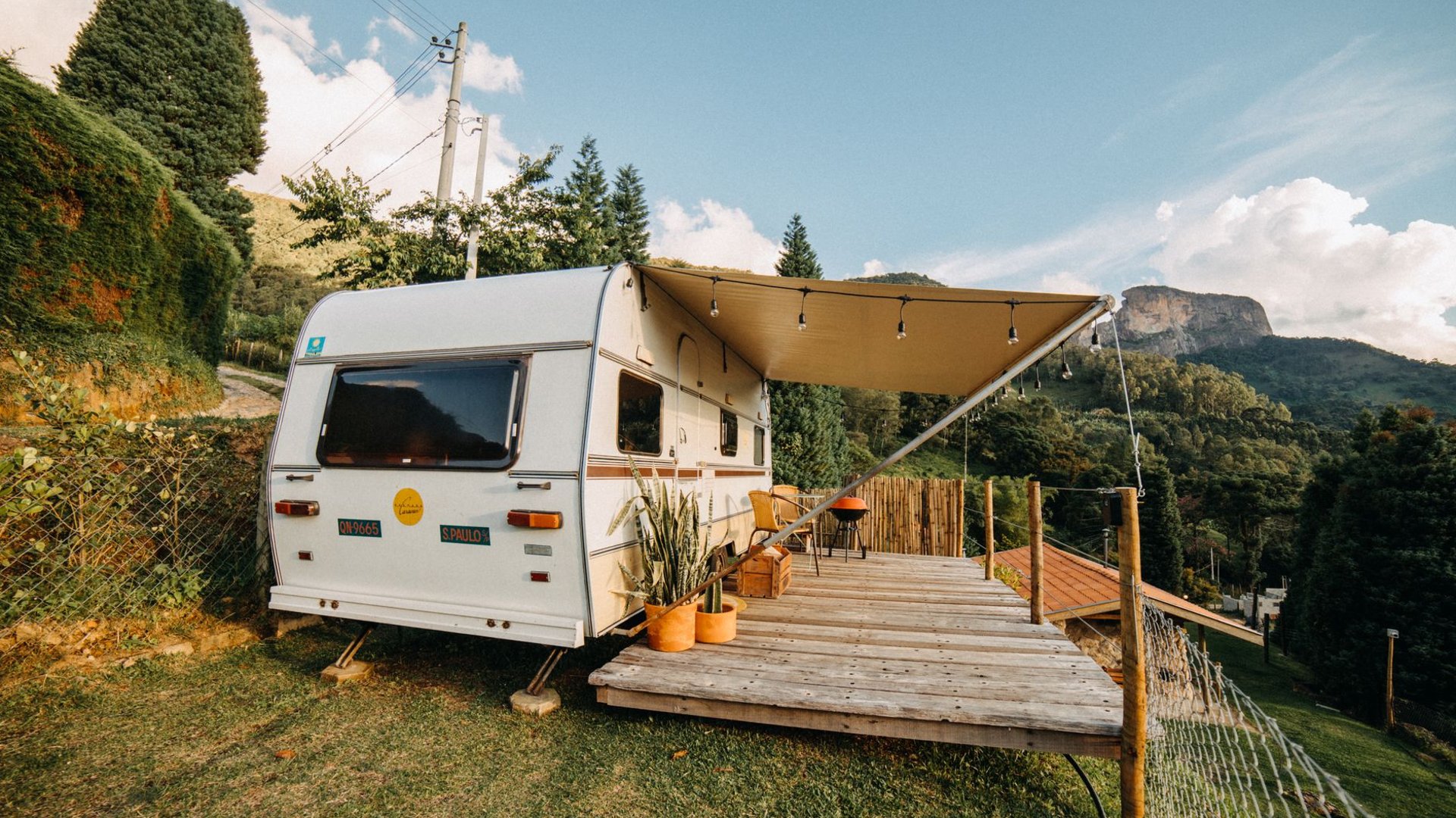 Familie sitzt vor einem Wohnwagen mit Vorzelt auf dem Campingplatz
