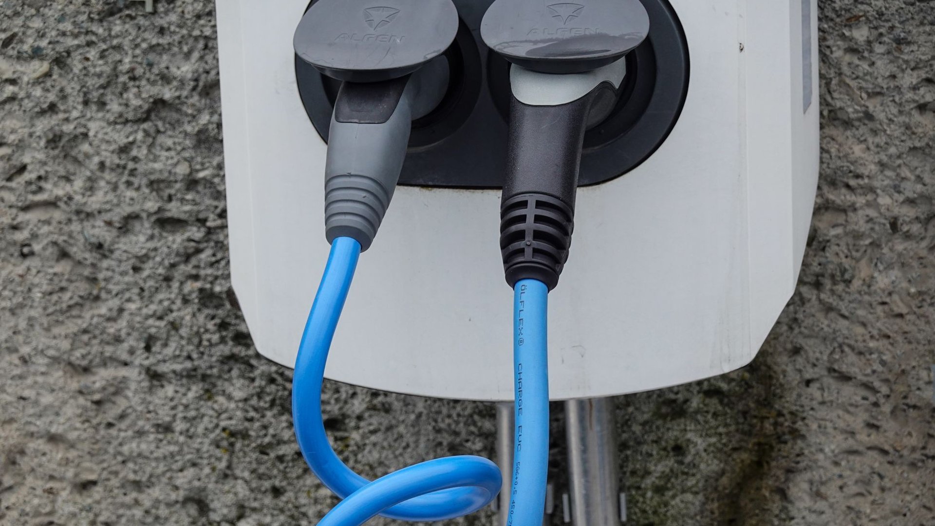 Zwei Stecker mit blauen Kabeln an einem Stromanschluss im Freien