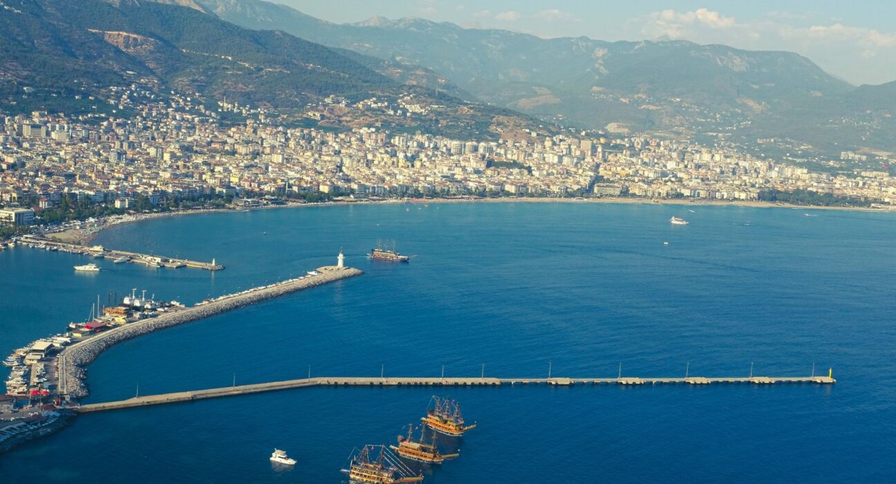 Mittelmeerküste mit Strand, türkisfarbenem Wasser und Bergen im Hintergrund