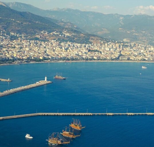 Mittelmeerküste mit Strand, türkisfarbenem Wasser und Bergen im Hintergrund