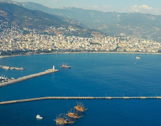 Mittelmeerküste mit Strand, türkisfarbenem Wasser und Bergen im Hintergrund