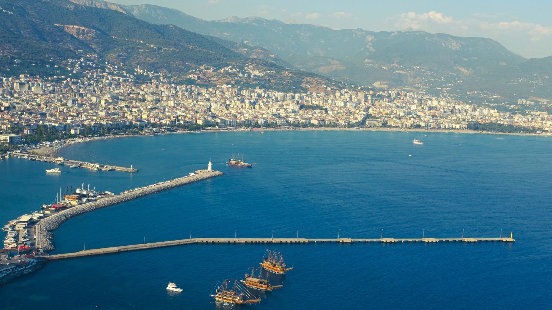 Mittelmeerküste mit Strand, türkisfarbenem Wasser und Bergen im Hintergrund