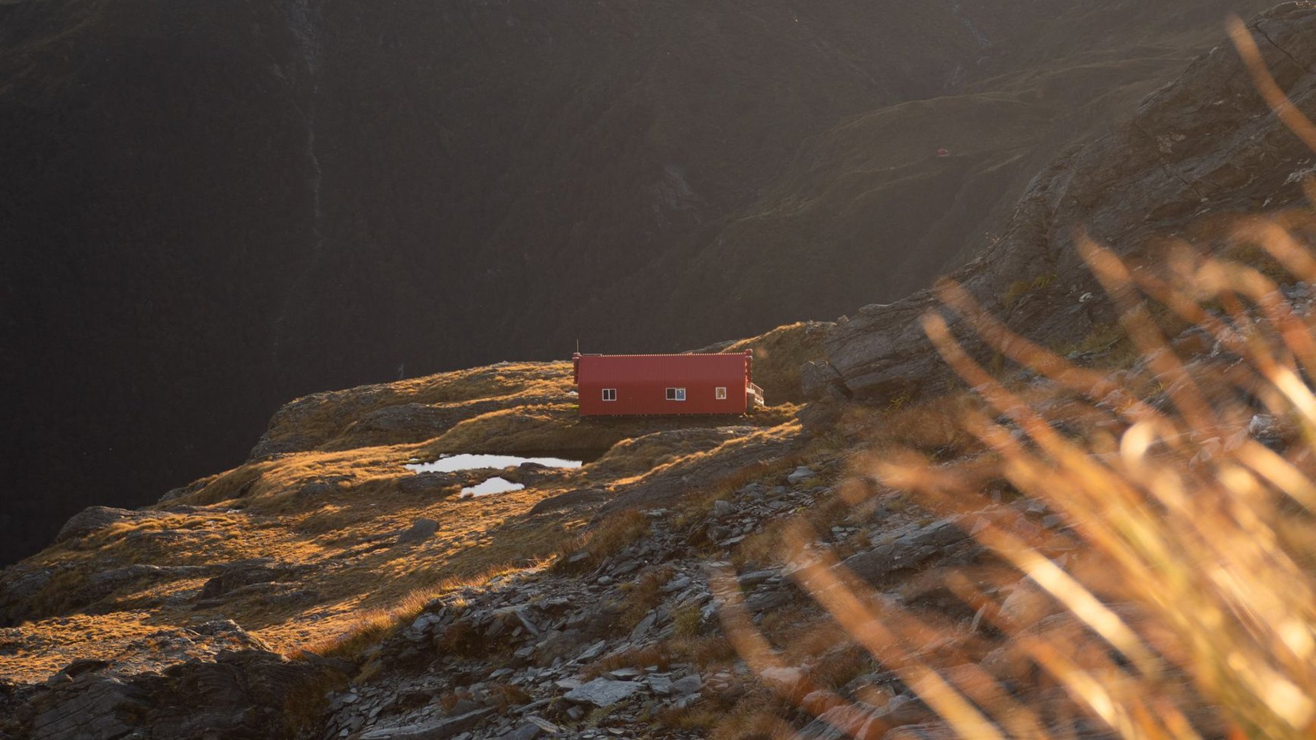 Rote Hütte auf einem Felsrücken im Abendlicht